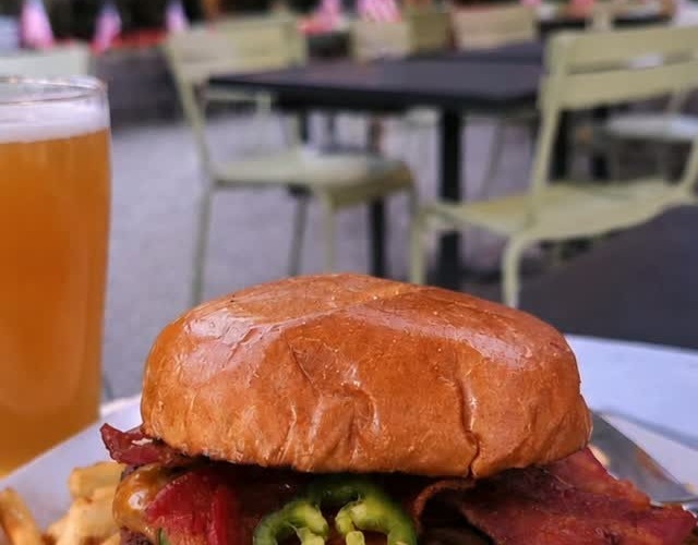 Bacon cheeseburger with fries and a draft beer on the outdoor patio